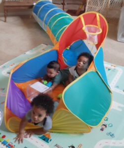 Three children playing in a tunnel on the floor