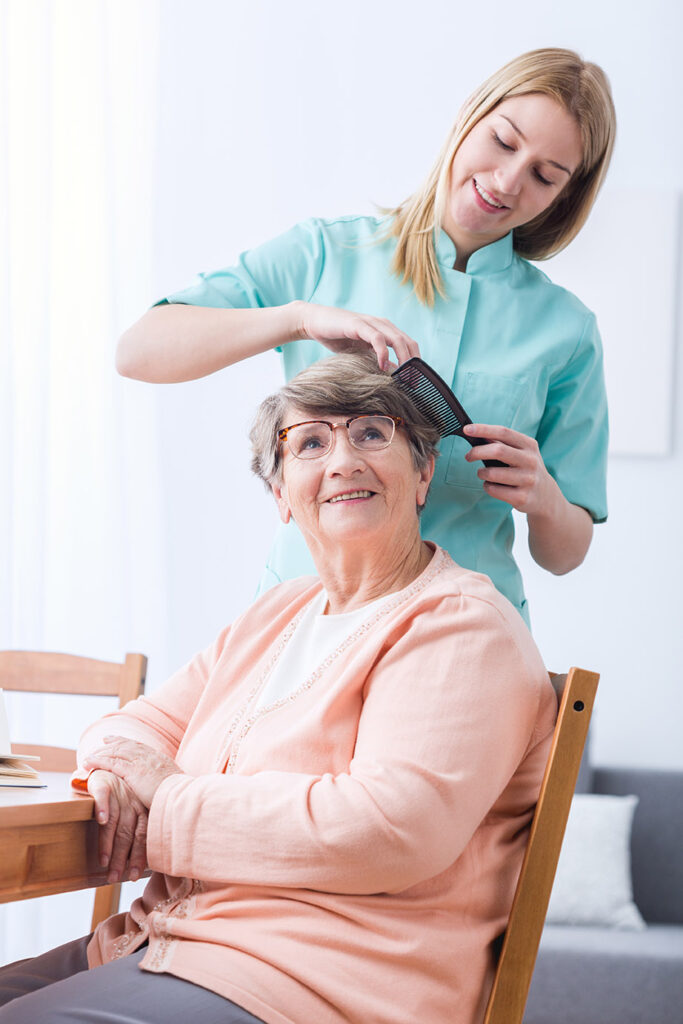 A woman is combing the hair of an older person.